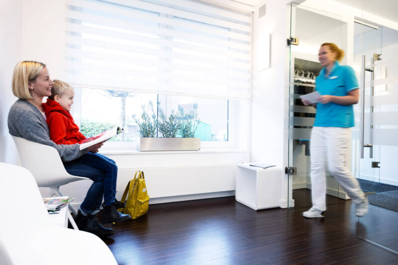 Foto Patientin mit Kind auf dem Schoß im Wartezimmer der Zahnarztpraxis