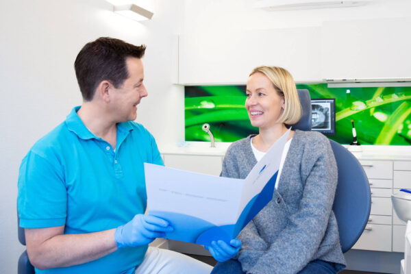 Foto Zahnarzt Dr. Andreas Koch im Gespräch mit lächelnder Patientin